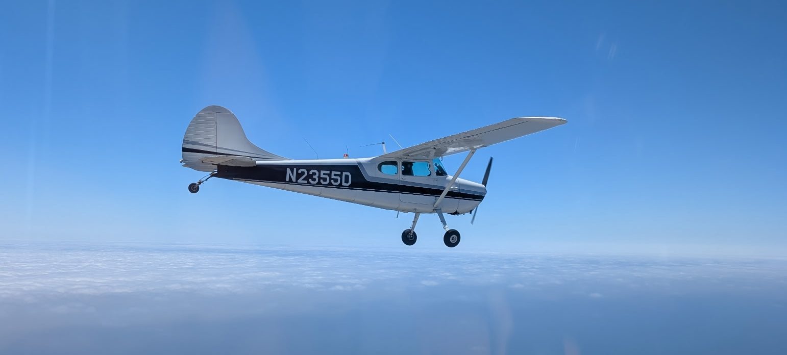 Cessna 170 in flight above the marine layer off the California coast