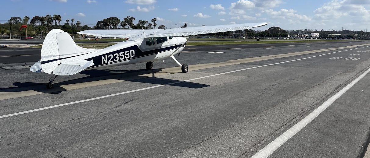 Cessna 170 on the airport ramp, palm trees and the LA basin beyond