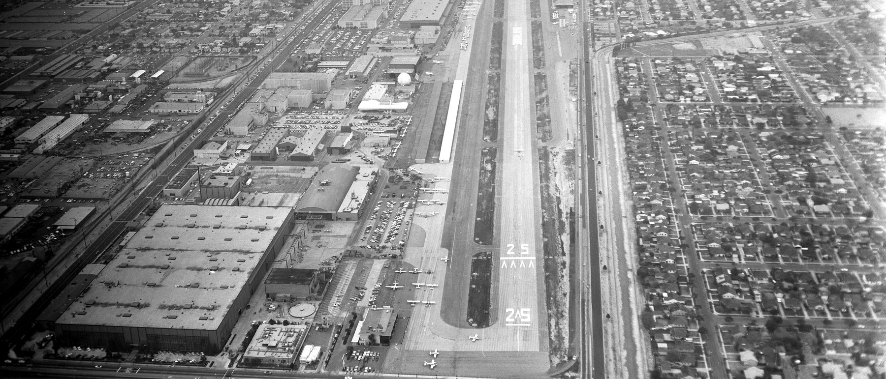 Aerial view of Hawthorne Municipal Airport in 1972, light aircraft parked along the ramp beside the runway 25 threshold